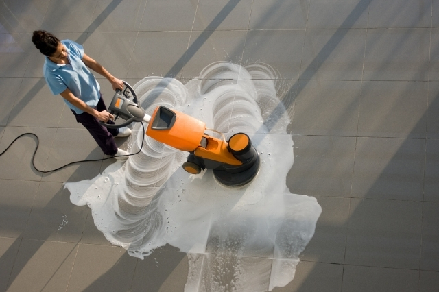 janitor performing floor cleaning with an automated floor cleaning machine